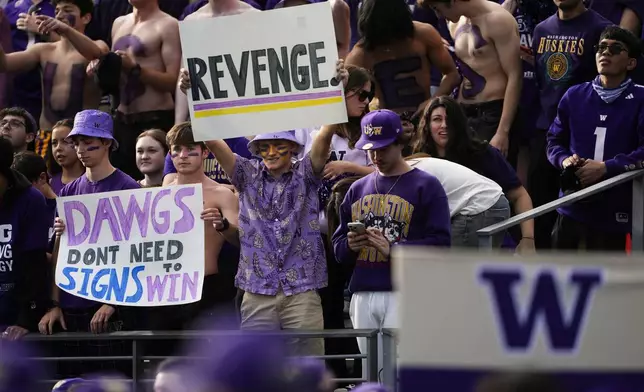 Washington fans hold signs before an NCAA college football game between Washington and Michigan, Saturday, Oct. 5, 2024, in Seattle. (AP Photo/Lindsey Wasson)