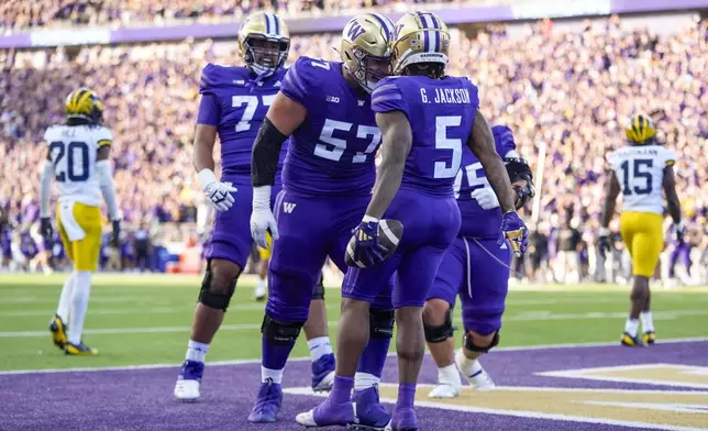 Washington wide receiver Giles Jackson (5) celebrates his touchdown with offensive lineman Enokk Vimahi (57) against Michigan during the first half of an NCAA college football game Saturday, Oct. 5, 2024, in Seattle. (AP Photo/Lindsey Wasson)