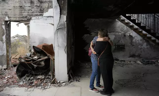 People hug at the house of Maayan and Yuval Bar killed by Hamas, as Israel marks the one-year anniversary of the Hamas attack on Israel, at the Kibbutz Be'eri, an Israeli communal farm on the Gaza border, on Monday, Oct. 7, 2024. (AP Photo/Ohad Zwigenberg)