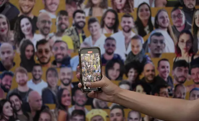 A woman takes photos at a mural with portraits of the victims at the site of the Nova music festival, where hundreds of revelers were killed and abducted by Hamas and taken into Gaza, on the one-year anniversary of the attack, near Kibbutz Reim, southern Israel, Monday, Oct. 7, 2024. (AP Photo/Ariel Schalit)