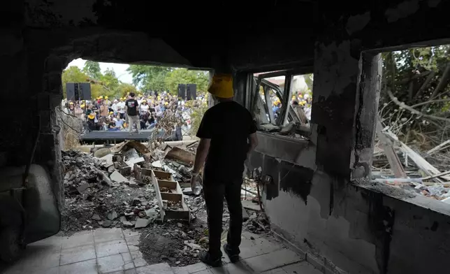 A man looks at a battle-scarred home at the Kibbutz Be'eri, an Israeli communal farm on the Gaza border, as Israel marks the one-year anniversary of the Hamas attack on Israel on Monday, Oct. 7, 2024. (AP Photo/Ohad Zwigenberg)