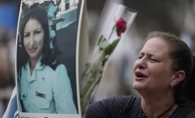 Victoria stands in front a picture of her sister, Yulia Waxer Daunt, as she visits the site of the Nova music festival, where hundreds of revelers were killed and abducted by Hamas and taken into Gaza, on the one-year anniversary of the attack, near Kibbutz Reim, southern Israel, Monday, Oct. 7, 2024. (AP Photo/Ariel Schalit)