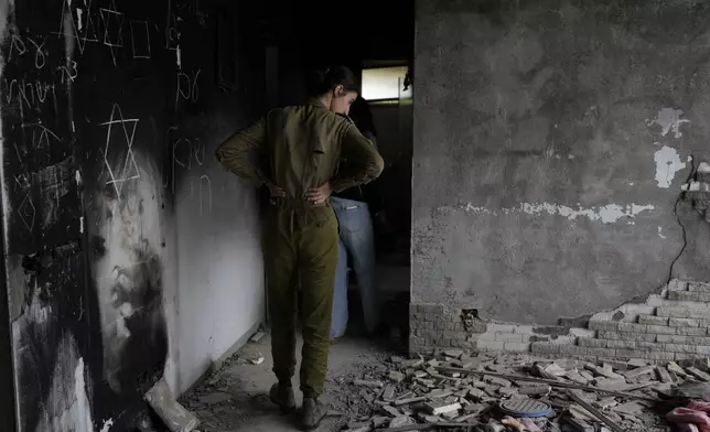 An Israeli soldier looks at a battle-scarred home at the Kibbutz Be'eri, an Israeli communal farm on the Gaza border, as Israel marks the one-year anniversary of the Hamas attack on Israel on Monday, Oct. 7, 2024. (AP Photo/Ohad Zwigenberg)