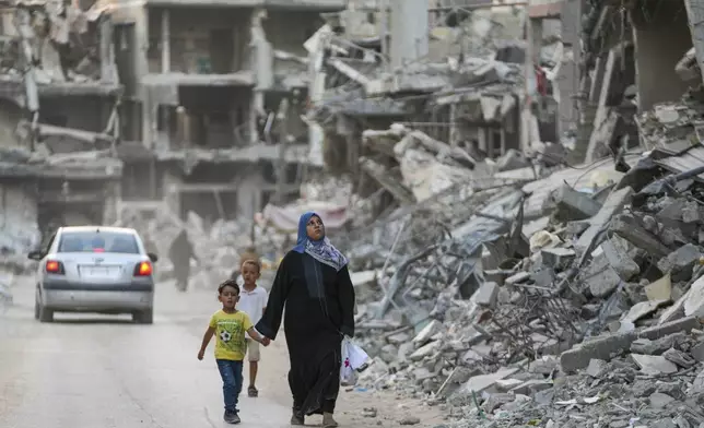 Palestinians walk through the destruction left by the Israeli air and ground offensive on Khan Younis, Gaza Strip, Thursday, Sept. 12, 2024. (AP Photo/Abdel Kareem Hana)