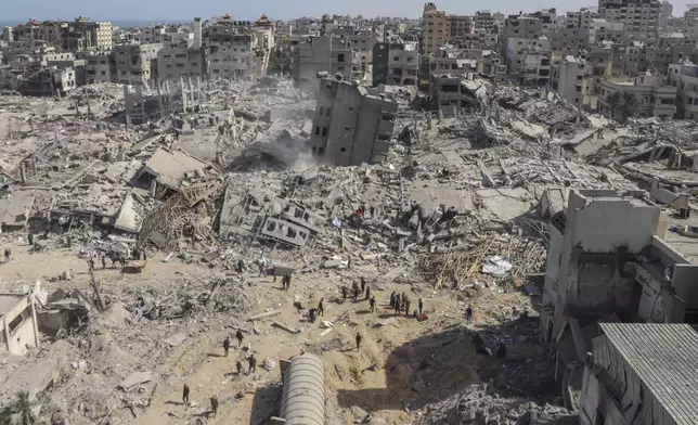 FILE - Palestinians walk through the destruction left by the Israeli air and ground offensive on the Gaza Strip near Shifa Hospital in Gaza City, Monday, April 1, 2024. (AP Photo/Mohammed Hajjar, File)