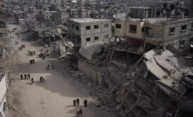 FILE - Palestinians walk through the destruction in the wake of an Israeli air and ground offensive in Khan Younis, southern Gaza Strip, Monday, April 8, 2024. (AP Photo/Fatima Shbair, File)