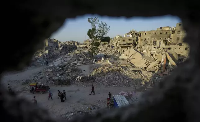 Palestinians walk through the destruction left by the Israeli air and ground offensive on Khan Younis, Gaza Strip, Thursday, Sept. 12, 2024. (AP Photo/Abdel Kareem Hana)