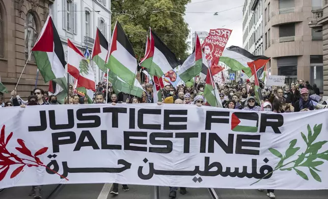 Protesters hold placards and Palestinian flags during a rally in support of the Palestinian people, in Basel, Switzerland, Saturday Oct. 5, 2024. (Ennio Leanza/Keystone via AP)