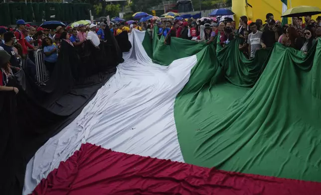 Demonstrators unfurl a Palestinian flag during march to the United Nations office in a government organized demonstration to show support for the Palestinian people in Caracas, Venezuela, Saturday, Oct. 5, 2024, days before the one-year anniversary of Hamas' attack in southern Israel and Israel's response to go to war on Hamas. (AP Photo/Ariana Cubillos)