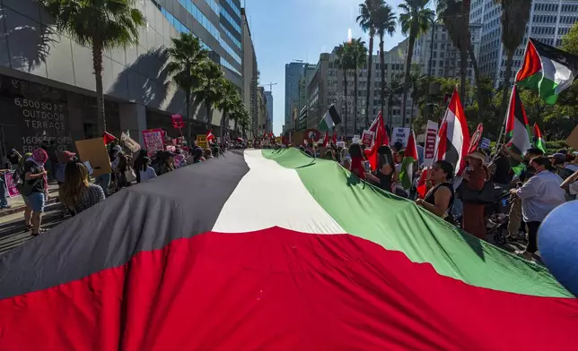 Palestinian supporters hold a large Palestinian flag as they rally in downtown Los Angeles on Saturday, Oct. 5, 2024, two days before the anniversary of Hamas-led groups' attack in Israeli territory outside of Gaza on Oct. 7, 2023. (AP Photo/Damian Dovarganes)