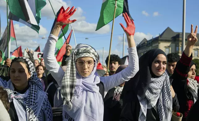 A participant in a pro-Palestinian rally holds up her red-painted hands on the Steintordamm, in Hamburg, Germany, Saturday, Oct. 5, 2024. (Georg Wendt/dpa via AP)