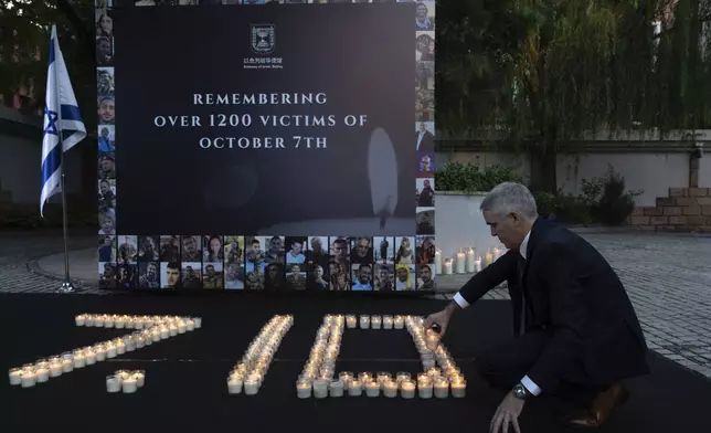 A staffer lights candles at a memorial for victims on the one-year anniversary of the Hamas attack on Israel at the Israeli embassy in Beijing, Monday, Oct. 7, 2024. (AP Photo/Ng Han Guan)