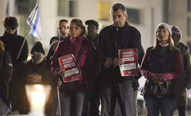 People attend the reading the names of the victims of the Hamas attack on Israel during a commemoration to mark the first anniversary of the attack, at the Brandenburg Gate in Berlin, Germany, Monday, Oct. 7, 2024. (AP Photo/Markus Schreiber)