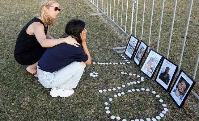 Two women console each other after making a makeshift memorial as members of the Jewish community gather at a park to mark the anniversary of the Oct. 7, 2023, Hamas attack, Sydney, Australia, on Monday, Oct. 7, 2024. (AP Photo/Rick Rycroft)