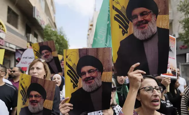 Palestinian activists hold posters with pictures of late Hezbollah leader Hassan Nasrallah during a protest marking the one year anniversary of the Israel Hamas war, in the West Bank city of Ramallah, Monday, Oct. 7, 2024. (AP Photo/Nasser Nasser)