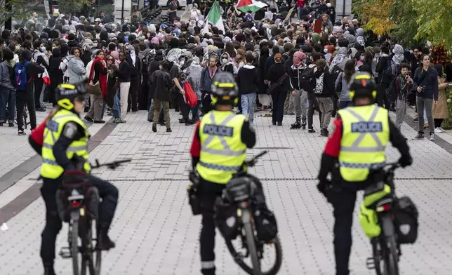 Police watch as attendees march near McGill University campus during a pro-Palestinian demonstration on the anniversary of a Hamas attack on Israel that triggered the ongoing war in Gaza, in Montreal, Canada, Monday, Oct. 7, 2024. (Christinne Muschi/The Canadian Press via AP)