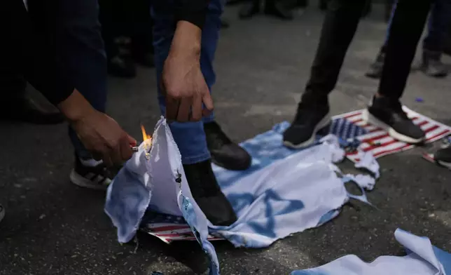 Palestinian activists burn IsraelI and U.S. flags during a protest marking the one year anniversary of the Israel Hamas war, in the West Bank city of Ramallah, Monday, Oct. 7, 2024. (AP Photo/Nasser Nasser)