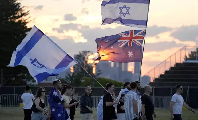 People carry flags as members of the Jewish community gather at a park in Sydney, Australia, on Monday, Oct. 7, 2024, as mourners marked the anniversary of the Oct. 7, 2023, attack in Israel. (AP Photo/Rick Rycroft)