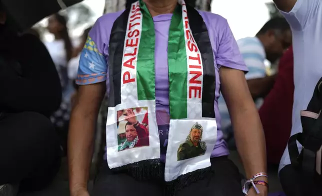 Rosa Teran wears a scarf with the image of Venezuelan late president Hugo Chavez, left, and late Palestinian leader Yasser Arafat, right, during a march to the United Nations office to show support for the Palestinian people in Caracas, Venezuela, Saturday, Oct. 5, 2024, days before the one-year anniversary of Hamas' attack in southern Israel and Israel's response to go to war on Hamas. (AP Photo/Ariana Cubillos)