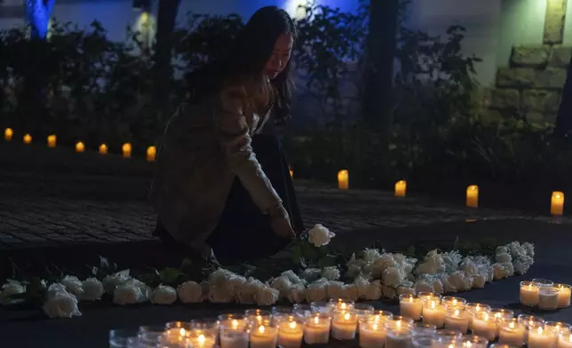 An attendee lays a flower at a memorial for victims during the one-year anniversary of the Hamas attack on Israel at the Israel embassy in Beijing, Monday, Oct. 7, 2024. (AP Photo/Ng Han Guan)