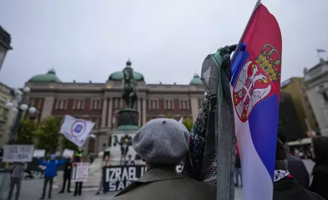 A woman holds a Serbian flag during a pro-Palestinian gathering in Belgrade, Serbia, Saturday, Oct. 5, 2024. (AP Photo/Darko Vojinovic)