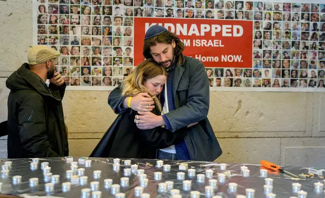 People embrace after lightning candles at a ceremony marking the first anniversary of the Hamas spearheaded attacks on Israel, at the synagogue of the Chabad community in Berlin, Germany, Monday, Oct. 7, 2024. (AP Photo/Markus Schreiber)