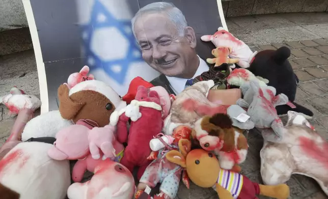 Israeli Prime Minister Benjamin Netanyahu's portrait is covered with toys that symbolize being stained with blood during a protest outside Israel Economic and Cultural Office in Taipei, Taiwan, Monday, Oct. 7, 2024. (AP Photo/Chiang Ying-ying)