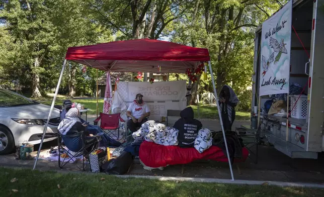 Protesters, including Mike Madanat, center in the white t-shirt, gather near Ohio Democratic Rep. Greg Landsman's Cincinnati residence, Monday, Oct. 7, 2024. (AP Photo/Carolyn Kaster)