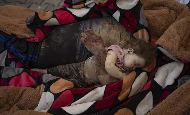 The bodies of a father and his child killed in the Israeli bombardment of the Gaza Strip, lie in front of the morgue at Al-Aqsa Hospital in Deir Al-Balah, Sunday, Oct. 22, 2023. (AP Photo/Fatima Shbair)