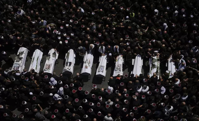 Mourners from the Druze minority surround the bodies of some of the 12 children and teens killed in a rocket strike at a soccer field, in the village of Majdal Shams at the Israeli-controlled Golan Heights, Sunday, July 28, 2024. (AP Photo/Leo Correa)