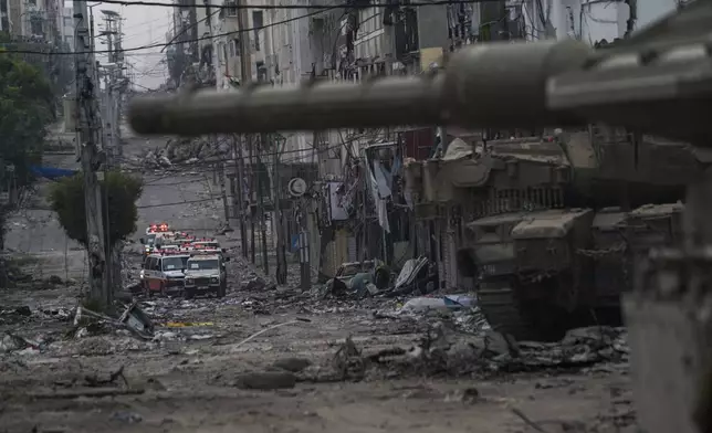 Ambulances are seen on a road near an Israeli forces tank during an Israeli army ground operation in the Gaza Strip, Wednesday, Nov. 22, 2023. (AP Photo/Victor R. Caivano)