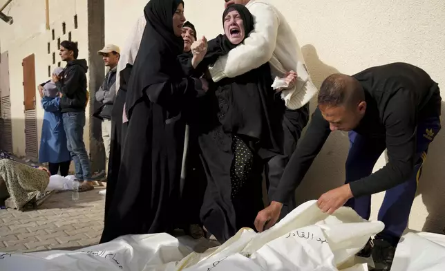 Palestinians mourn relatives killed in the Israeli bombardment of the Gaza Strip in front of the morgue in Deir al Balah, Sunday, Nov. 19, 2023. (AP Photo/Hatem Moussa)