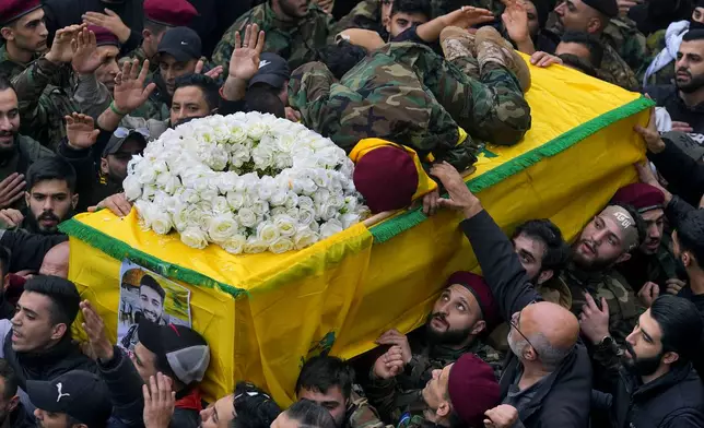 Hussein, brother of Hezbollah fighter Ali Hassan al-Atat, who was killed by an Israeli strike, lies on top of his brother's coffin during his funeral procession in the southern Beirut suburb of Dahiyeh, Lebanon, Thursday, Dec. 7, 2023. (AP Photo/Bilal Hussein)