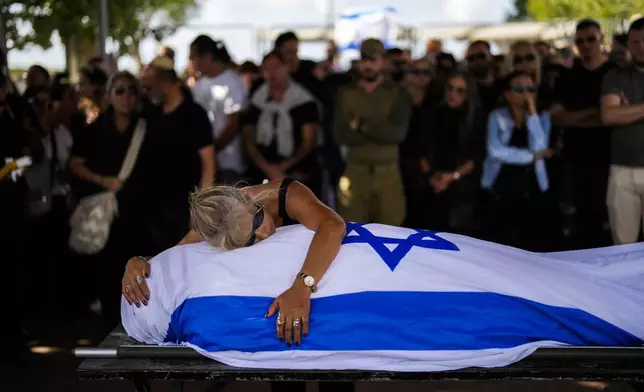 Antonio Macías' mother cries over her son's body covered with the Israeli flag at Pardes Haim cemetery in Kfar Saba, near Tel Aviv, Israel, Sunday, Oct. 15, 2023. (AP Photo/Francisco Seco)