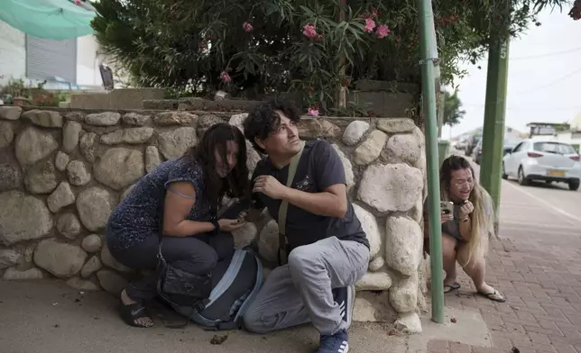 Israelis take cover from the incoming rocket fire from the Gaza Strip in Ashkelon, southern Israel, Wednesday, Oct. 11, 2023. (AP Photo/Leo Correa)