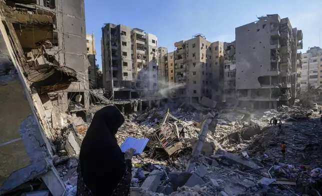 A woman reads the Quran at the site of the assassination of Hezbollah leader Hassan Nasrallah in Beirut's southern suburbs, Sunday, Sept. 29, 2024. (AP Photo/Hassan Ammar)