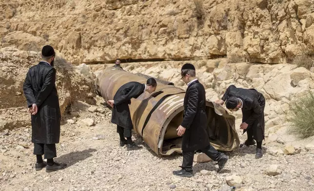 Ultra-Orthodox Jews observe part of an intercepted ballistic missile that fell in the desert near the city of Arad, Israel, Sunday, April 28, 2024. (AP Photo/ Ohad Zwigenberg)