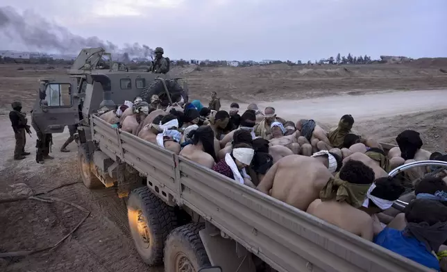 Israeli soldiers stand by a truck packed with bound and blindfolded Palestinian detainees, in Gaza, Friday, Dec. 8, 2023. (AP Photo/Moti Milrod, Haaretz)