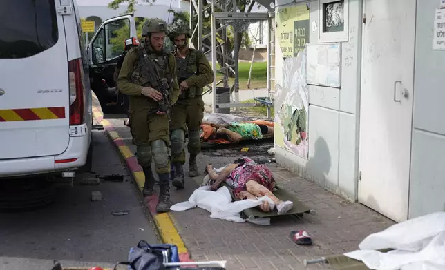 Israeli soldiers walk by civilians killed by Palestinian militants in Sderot, Israel, on Saturday, Oct. 7, 2023. (AP Photo/Ohad Zwigenberg)