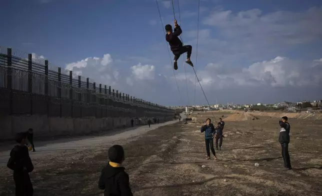 Palestinians displaced by the Israeli bombardment of the northern Gaza Strip play next to the border with Egypt, in Rafah, southern Gaza, Sunday, Jan. 14, 2024. (AP Photo/Fatima Shbair)