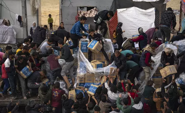 Palestinians take food from a humanitarian aid truck as it crosses into the Gaza Strip in Rafah, Sunday, Dec. 17, 2023. (AP Photo/Fatima Shbair)