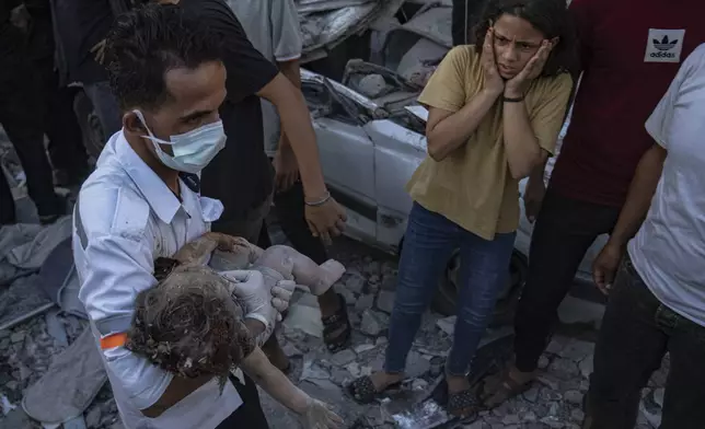 A Palestinian reacts as a child is carried from the rubble of a building after an airstrike in Khan Younis, Gaza Strip, Saturday, Oct. 21, 2023. (AP Photo/Fatima Shbair)