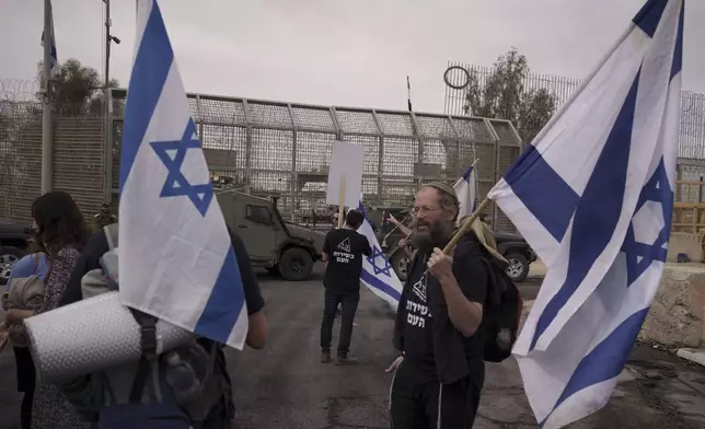 People stand in front of a gate at the Nitzana border crossing with Egypt in southern, Israel, Monday, Feb. 12, 2024, protesting against the humanitarian aid to enter Gaza until all the hostages are released. (AP Photo/Leo Correa)