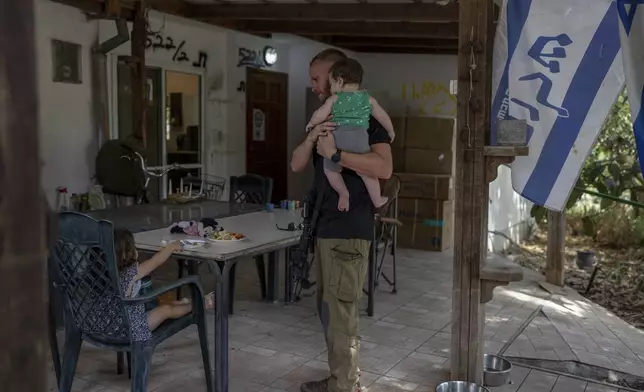 A member of Kibbutz Kfar Aza civilian defense squad with his family at their home in the near-empty kibbutz, Monday, Sept. 16, 2024. (AP Photo/Ohad Zwigenberg)