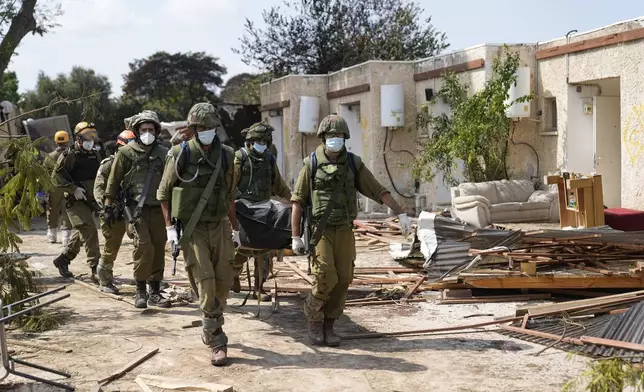 FILE- Israeli soldiers carry bodies of Israelis in Kibbutz Kfar Aza on Oct. 10, 2023. (AP Photo/Ohad Zwigenberg, File)