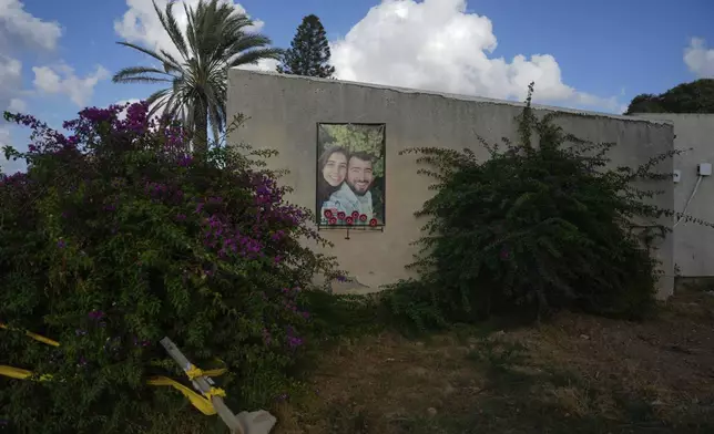 A picture of Niv Raviv, 27 and Nirel Zini, 31, a couple killed by Hamas militants on Oct. 7 in Kibbutz Kfar Aza, hangs on a wall of their old home nearly a year after their killing in the southern border community, Israel, Monday, Sept. 16, 2024. (AP Photo/Ohad Zwigenberg)