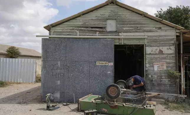 A resident of Kibbutz Kfar Aza, southern Israel, repairs a freight cart nearly a year after a deadly Hamas onslaught on the kibbutz, Monday, Sept. 16, 2024. (AP Photo/Ohad Zwigenberg)