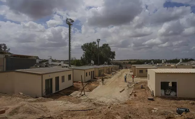 Construction workers build temporary homes where former residents of Kibbutz Kfar Aza, a community partially destroyed in the Oct. 7 Hamas attack on Israel, will live in Kibbutz Ruhama, southern Israel, Tuesday, Sept. 17, 2024. (AP Photo/Ohad Zwigenberg)