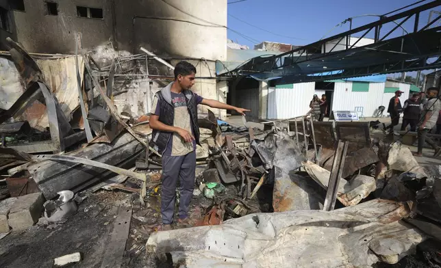 Mohamed al-Dalu gestates to the site where his brother, Shaban, was killed in a fire after an Israeli strike hit a tent area in the courtyard of Al Aqsa Martyrs hospital in Deir al-Balah, Gaza Strip, Wednesday, Oct. 16, 2024. (AP Photo/Abdel Kareem Hana)