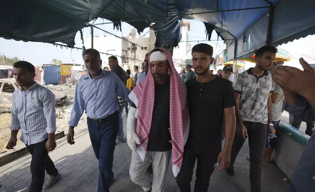 Ahmad al-Dalu, center, whose son, Shaban, was killed in a fire after an Israeli strike hit a tent area in the courtyard of Al Aqsa Martyrs hospital in Deir al-Balah, Gaza Strip, at the site on Wednesday, Oct. 16, 2024. (AP Photo/Abdel Kareem Hana)